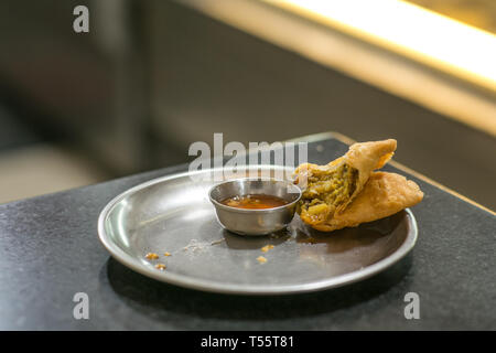 Ein Frieden der Hälfte gegessen Samosa auf einer Platte in einem Restaurant Stockfoto
