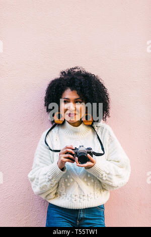 Junge Frau mit Kamera gegen Rosa Wand Stockfoto