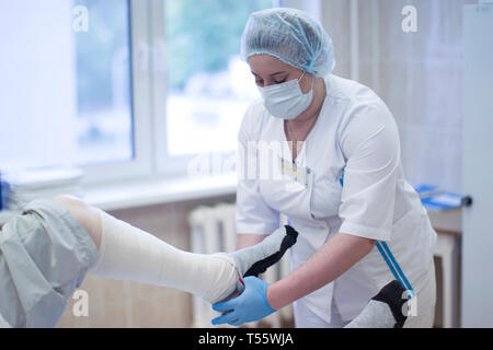 Krankenschwester Bandagen Bein des Patienten Stockfoto