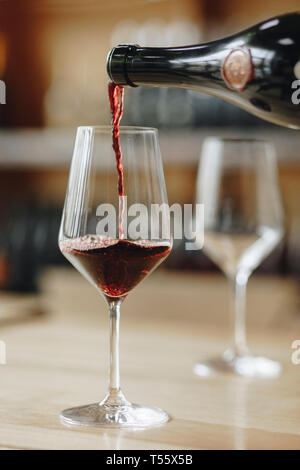 Rotwein gegossen aus Flasche in wineglass Stockfoto