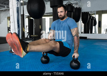 Man Balancieren auf Kettlebells in der Turnhalle Stockfoto