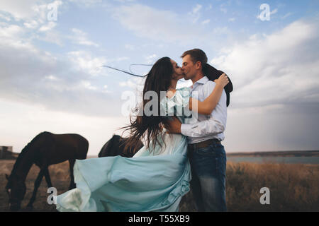 Junges Paar Küssen in Feld von Pferden Stockfoto