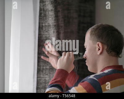 Man schaut aus dem Fenster mit dem Fernglas Stockfoto