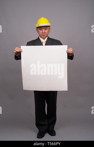 Reifen asiatischen Bau Unternehmer gegen grauer Hintergrund Stockfoto