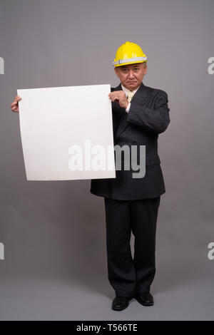 Reifen asiatischen Bau Unternehmer gegen grauer Hintergrund Stockfoto