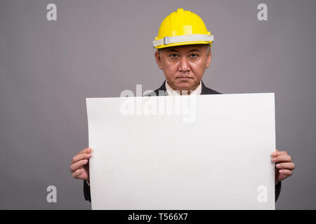 Reifen asiatischen Bau Unternehmer gegen grauer Hintergrund Stockfoto