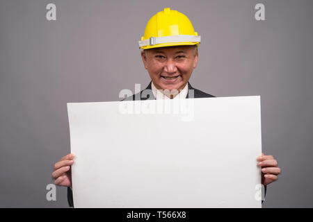 Reifen asiatischen Bau Unternehmer gegen grauer Hintergrund Stockfoto