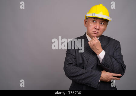 Reifen asiatischen Bau Unternehmer gegen grauer Hintergrund Stockfoto