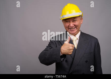 Reifen asiatischen Bau Unternehmer gegen grauer Hintergrund Stockfoto