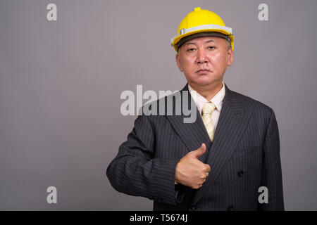 Reifen asiatischen Bau Unternehmer gegen grauer Hintergrund Stockfoto