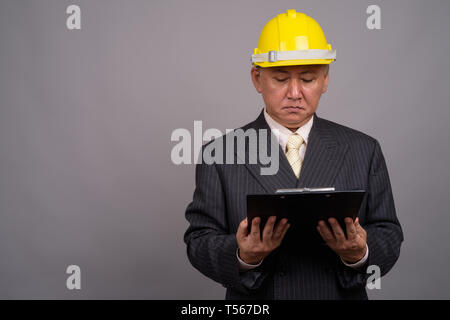 Reifen asiatischen Bau Unternehmer gegen grauer Hintergrund Stockfoto