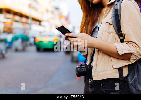 Junge asiatische Frau touristische Frau mit einem Handy in Bangkok, Thailand. Einberufung einer Kabine oder das Auffinden von Informationen während der Fahrt Konzept Stockfoto