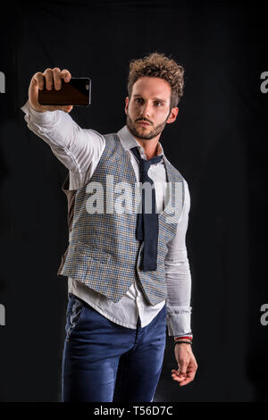 Schöner Mann mit Handy im Studio erschossen Stockfoto