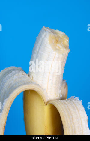 In der Nähe der Hälfte gegessen geschälte Banane auf blauem Hintergrund Stockfoto