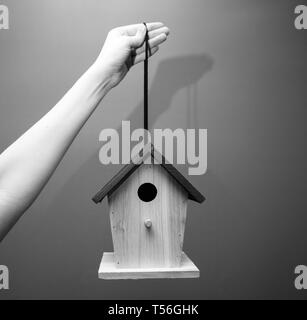 Erwachsene Frau Hand, die von einem Thread Vögel nisten Vogelhaus Haus im Garten an einem Baum installiert werden - Schwarz und Weiß gehängt Stockfoto