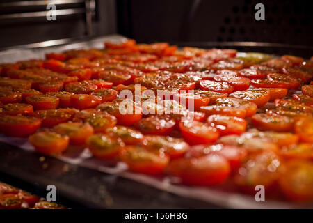 Schalen mit frischen Kirschtomaten auf Gestellen trocknen im Ofen Stockfoto