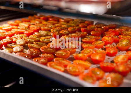 Schalen mit frischen Kirschtomaten auf Gestellen trocknen im Ofen Stockfoto