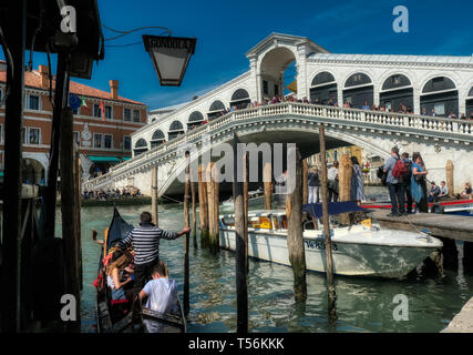 Venedig, Italien - 17 April 2019: Touristen, die für eine Fahrt in einer Gondel an der Rialtobrücke in Venedig, Italien, eine ikonische Brücke über den Canale Grande Stockfoto