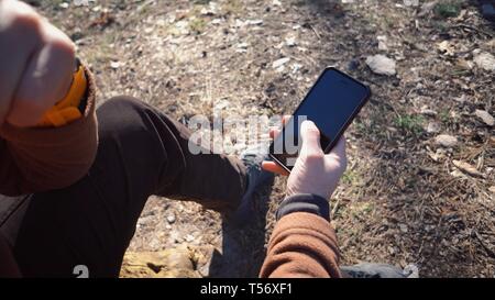 Thema Tourismus und Technologie. Jungen kaukasischen Mann Wandern touristische in einem Pinienwald verwendet die Technologie, Hand, Mobiltelefon, um den Bildschirm zu berühren. Gps Stockfoto