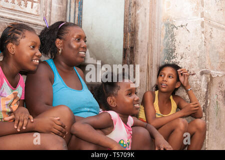 Havanna Kuba - 7. JULI 2012; Mutter und drei Tochter sitzen vor der Tür auf der Straße in glücklich und lächelnd vor Verfallenen Wand und Tür. Stockfoto