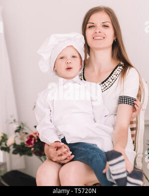 Portrait von Mama und ihrem kleinen Sohn in einem Küchenchef Anzug sitzen zusammen Stockfoto