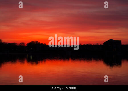 Paris, Frankreich. 21 Apr, 2019. Einen atemberaubenden Sonnenuntergang über dem Lac de La Sourderie, in der südwestlichen Pariser Vorort von Montigny-le-Bretonneux. Der Blick auf - sieht der Wohngegend Les Arcades du Lac, entworfen von spanischen Architekten Ricardo Bofill, und wird lokal als "Versailles für die Menschen" bekannt. Credit: Francesca Moore/Alamy leben Nachrichten Stockfoto