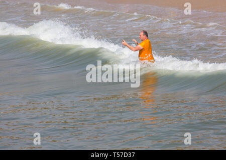 Bournemouth, Dorset, Großbritannien. 22 Apr, 2019. UK Wetter: Nach einem dunstigen Start das herrliche Wetter mit warmen und sonnigen Wetter fort, als beachgoers Kopf zum Meer die Wärme und Sonnenschein in Bournemouth Strände am Ostermontag zu genießen, bevor das Wetter ändert sich und die Rückkehr zur Arbeit. Der Mensch nimmt selfies in die Wellen im Meer springen. Credit: Carolyn Jenkins/Alamy leben Nachrichten Stockfoto