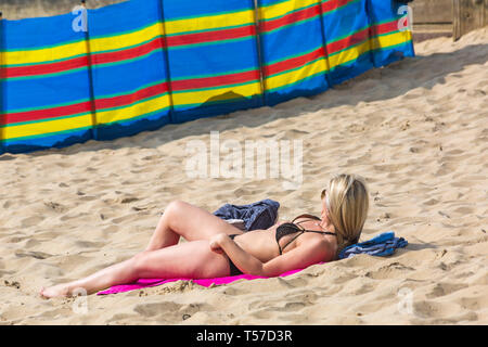 Bournemouth, Dorset, Großbritannien. 22 Apr, 2019. UK Wetter: Nach einem dunstigen Start das herrliche Wetter mit warmen und sonnigen Wetter fort, als beachgoers Kopf zum Meer die Wärme und Sonnenschein in Bournemouth Strände am Ostermontag zu genießen, bevor das Wetter ändert sich und die Rückkehr zur Arbeit. Frau im Bikini sonnen. Credit: Carolyn Jenkins/Alamy leben Nachrichten Stockfoto