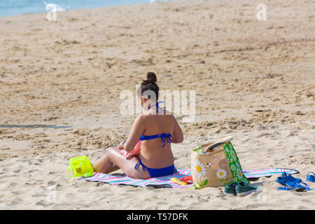 Bournemouth, Dorset, Großbritannien. 22 Apr, 2019. UK Wetter: Nach einem dunstigen Start das herrliche Wetter mit warmen und sonnigen Wetter fort, als beachgoers Kopf zum Meer die Wärme und Sonnenschein in Bournemouth Strände am Ostermontag zu genießen, bevor das Wetter ändert sich und die Rückkehr zur Arbeit. Frau in Blau Bikini Sonnenbaden am Strand. Credit: Carolyn Jenkins/Alamy leben Nachrichten Stockfoto