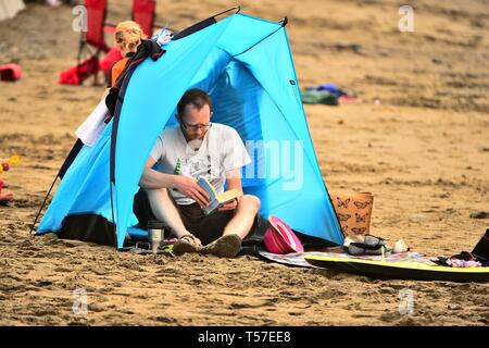 Aberystwyth, Ceredigion Wales UK Ostern Montag, 22. April 2019. Menschen am Meer in Aberystwyth genießen Lesen am Strand an einem weiteren Tag der schönen warmen Wetter, zwar leicht bewölkt und nicht so heiß wie die letzten rekordverdächtige Tage Foto: Keith Morris/Alamy leben Nachrichten Stockfoto