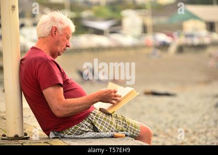 Aberystwyth, Ceredigion Wales UK Ostern Montag, 22. April 2019. Menschen am Meer in Aberystwyth genießen Lesen am Strand an einem weiteren Tag der schönen warmen Wetter, zwar leicht bewölkt und nicht so heiß wie die letzten rekordverdächtige Tage Foto: Keith Morris/Alamy leben Nachrichten Stockfoto