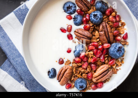 Hausgemachtes Müsli, Müsli mit Granatapfel Samen, Blaubeeren, Pekannuss und Joghurt. Gesundes Frühstück Schüssel. Ansicht von oben. Stockfoto
