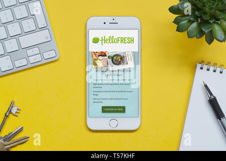 Ein iPhone mit den Hallo Frische website ruht auf einem gelben Hintergrund Tabelle mit einer Tastatur, Tasten, Notepad und Anlage (nur redaktionelle Nutzung). Stockfoto