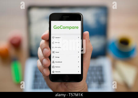 Ein Mann schaut auf seinem iPhone die zeigt die GoCompare Logo (nur redaktionelle Nutzung). Stockfoto