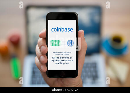 Ein Mann schaut auf seinem iPhone die zeigt die Coinbase Logo (nur redaktionelle Nutzung). Stockfoto