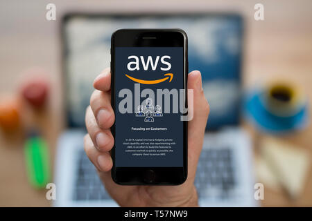 Ein Mann schaut auf seinem iPhone die zeigt die Amazon Web Services (AWS) Logo (nur redaktionelle Nutzung). Stockfoto