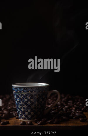 Kaffeetasse mit Bohnen und Dampf Stockfoto
