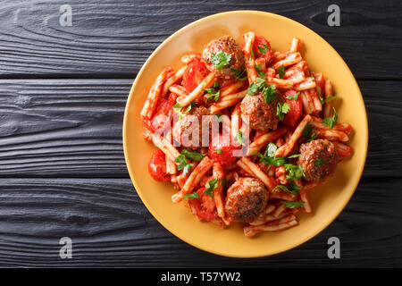 Pasta Casarecce Rezept mit Fleischbällchen, Kräuter und Käse in Tomatensauce closeup auf einem Teller auf den Tisch. horizontal oben Ansicht von oben Stockfoto