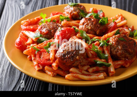 Pasta Casarecce Rezept mit Fleischbällchen, Kräuter und Käse in Tomatensauce closeup auf einem Teller auf den Tisch. Horizontale Stockfoto
