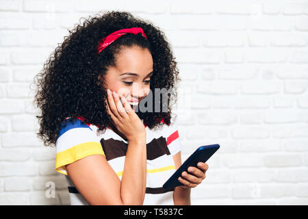 Happy african american woman reading gute Nachrichten auf Handy. Schwarze Mädchen zeigen, Freude und Glück für die Anzeige auf mobilen Telefon. Hispanische person wi Stockfoto