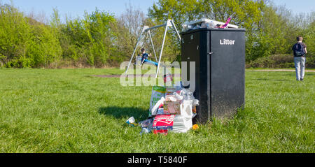 Überquellenden Mülleimer in einem Land Park mit Kinderspielplatz Stockfoto