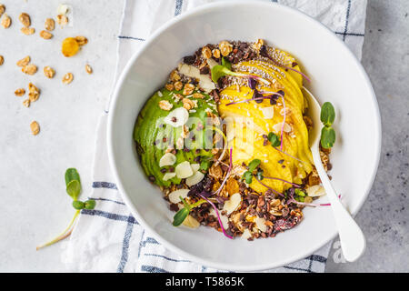 Müsli mit Avocado, Superfoods, Beeren und Früchte in einer weißen Schüssel. Auf Basis pflanzlicher Ernährung Konzept. Stockfoto