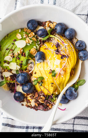 Müsli mit Avocado, Superfoods, Beeren und Früchte in einer weißen Schüssel. Auf Basis pflanzlicher Ernährung Konzept. Stockfoto