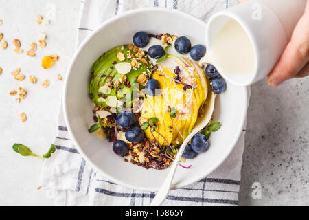 Müsli mit Avocado, Superfoods, Beeren und Früchte in einer weißen Schüssel. Auf Basis pflanzlicher Ernährung Konzept. Stockfoto