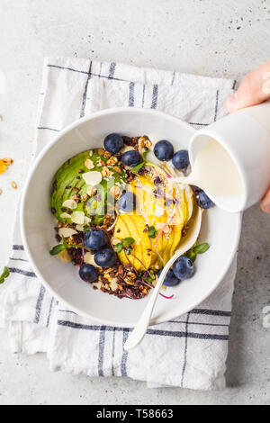 Müsli mit Avocado, Superfoods, Beeren und Früchte in einer weißen Schüssel. Auf Basis pflanzlicher Ernährung Konzept. Stockfoto