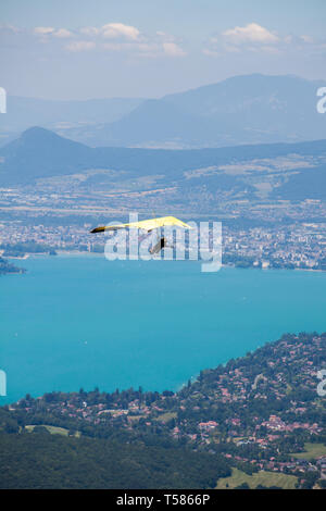 Hängegleiter Ausbilder Fliegen in Hängegleiter mit Kunden über See von Annecy durch Berge und Städte Stockfoto