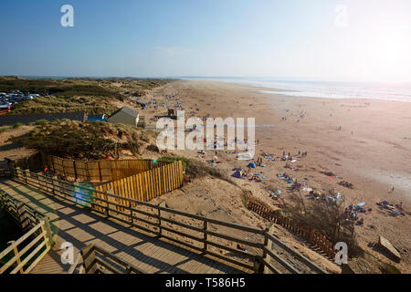 Touristen auf Saunton Sands Beach in North Devon an Ostern 2019 Hitzewelle mit Board Walk im Vordergrund Stockfoto