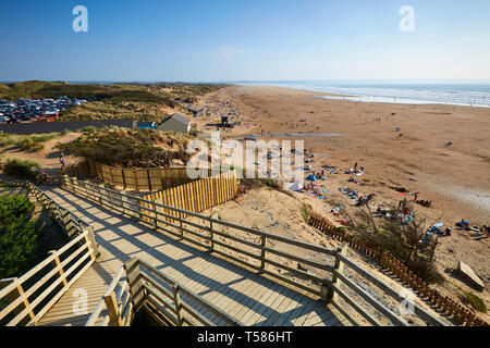 Touristen auf Saunton Sands Beach in North Devon an Ostern 2019 Hitzewelle mit Board Walk im Vordergrund Stockfoto