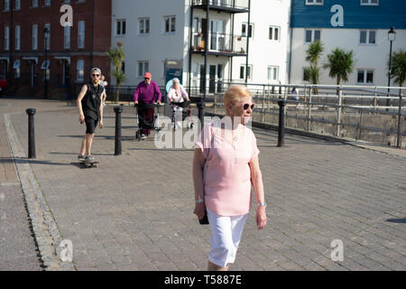 Eine Gruppe älterer Rentner, die an der Sommerpromenade spazieren gehen, mit einer Skateboarder, die in der Nähe von Little hampton in West Sussex, England vorbeikommt Stockfoto