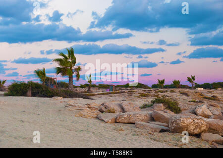 Bild von Landa Strand in Agia Napa, Zypern. Gelb Sand und Geröll gegen an einem warmen Abend im Herbst, dunkle Wolken am Himmel. Während der Goldenen Stunde Shot Stockfoto